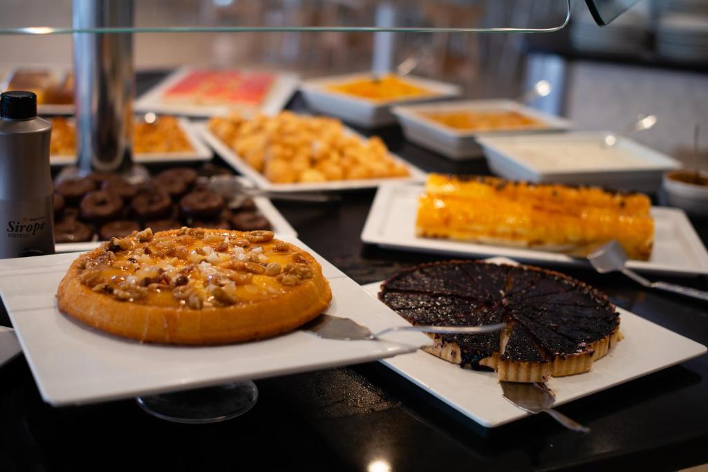 Deserts un saldumi, kas izkārtoti uz galda, tostarp riekstu kūka un tumšās šokolādes pīrāgs, ar sīrupu un citiem saldumiem.