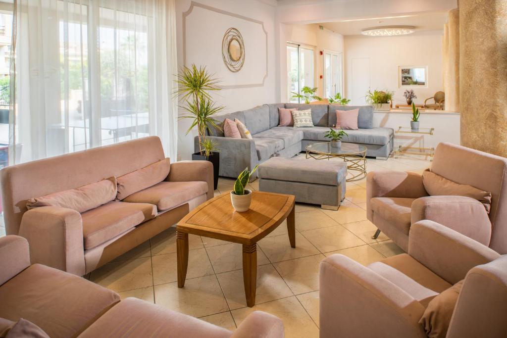 Moderns viesistabas interjers ar rozā un pelēkām mēbelēm, dabīgām augu dekorācijām un gaisīgu apgaismojumu. Komfortabls un stilīgs izkārtojums, kas rada patīkamu atmosfēru.