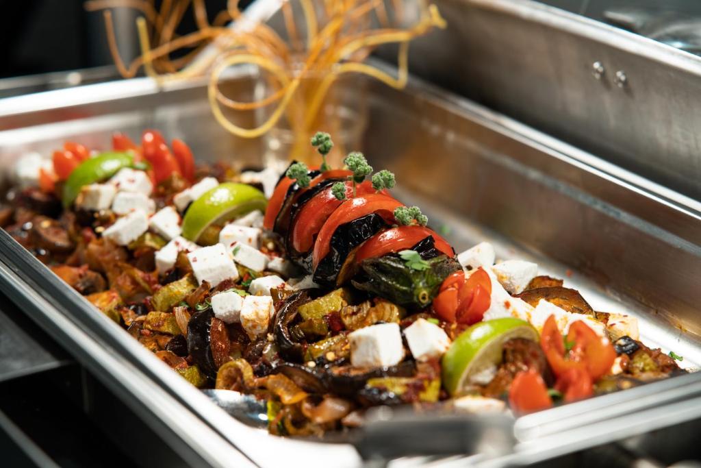 Svaiga un krāsaina dārzeņu uzkoda ar tomātiem, papriku un fetas sieru, pasniegta metāla traukā.