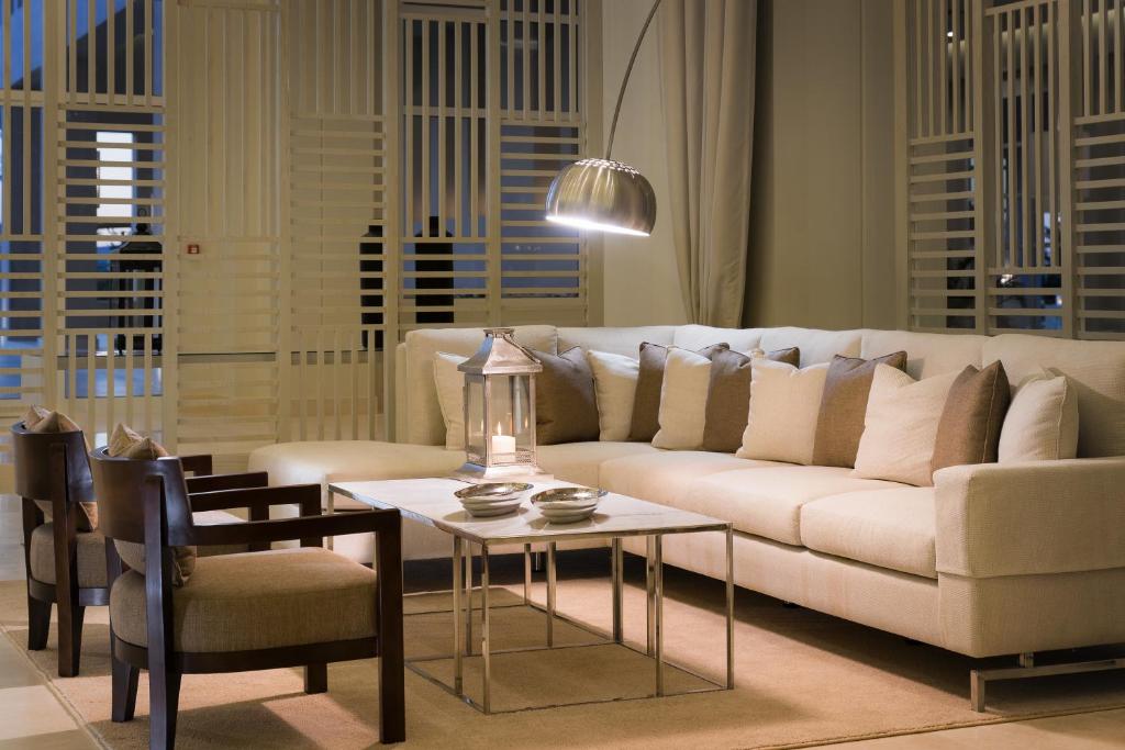 Mūsdienīgs viesistabas interjers ar vieglu dīvānu, dekoratīviem spilveniem un elegantu galdu, apgaismots ar stilīgu lampu. Svaiga un gaumīga atmosfēra.