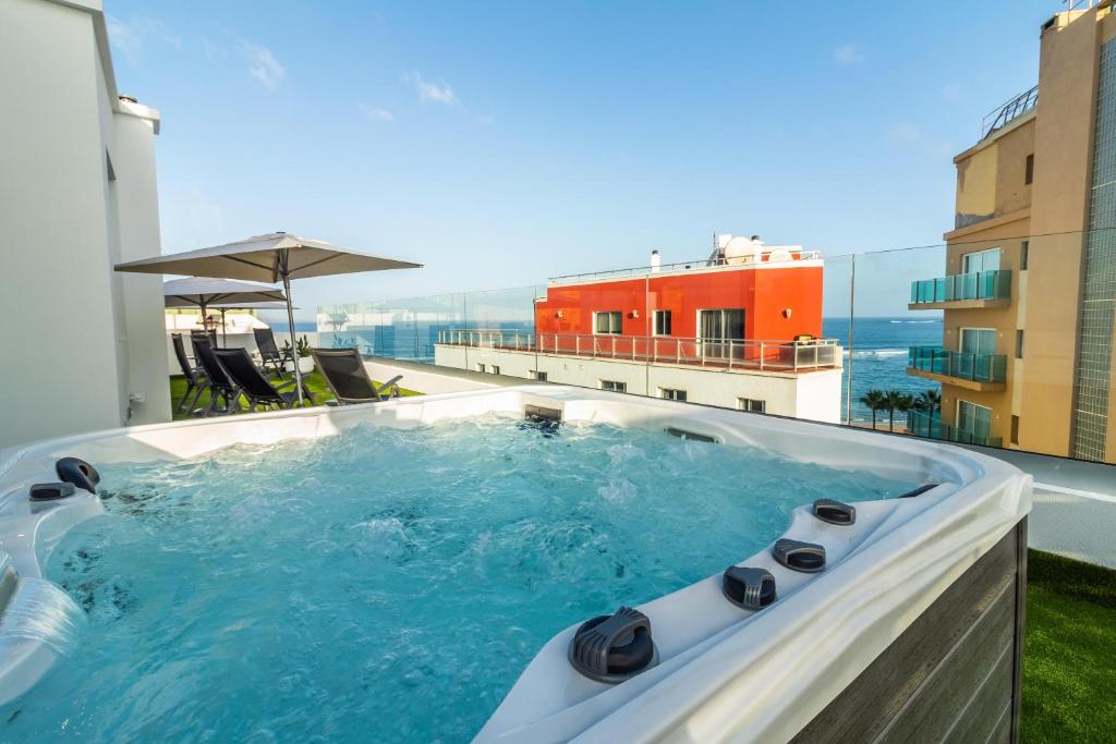 Apsildāms burbuļvannas skats no jumta terases ar jūru fona, apmeklētāji var baudīt relaksāciju saulainā vidē.