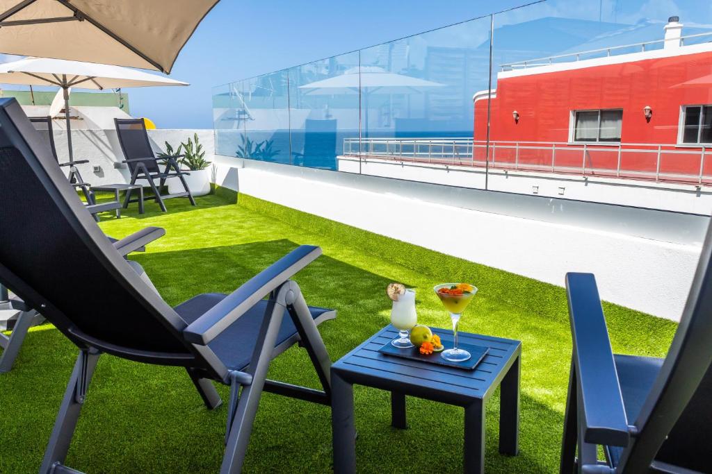 Atpūtas zona ar saulessargiem un šūpuļkrēslām, kur uz galda atrodas kokteiļi un augļi, skats uz jūru. Ideāla vieta relaksācijai un baudīšanai.