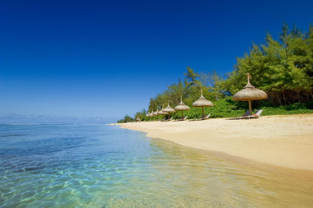 Skaista pludmale ar palmām un salmu jumtiem, kas izveidojusi relaksējošu atmosfēru. Kristāldzidrs ūdens un zila debesis rada idillisku ainavu.