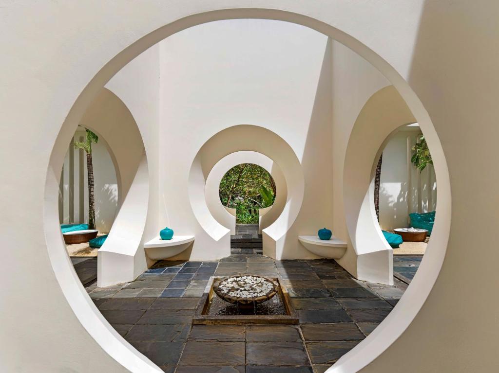 Mūsdienīgs arhitektūras interjers ar apaļām nišām, kas rada harmonisku atmosfēru. Gaisīgs un gaišs telpas dizains ar zaļumu un dekoratīviem elementiem.