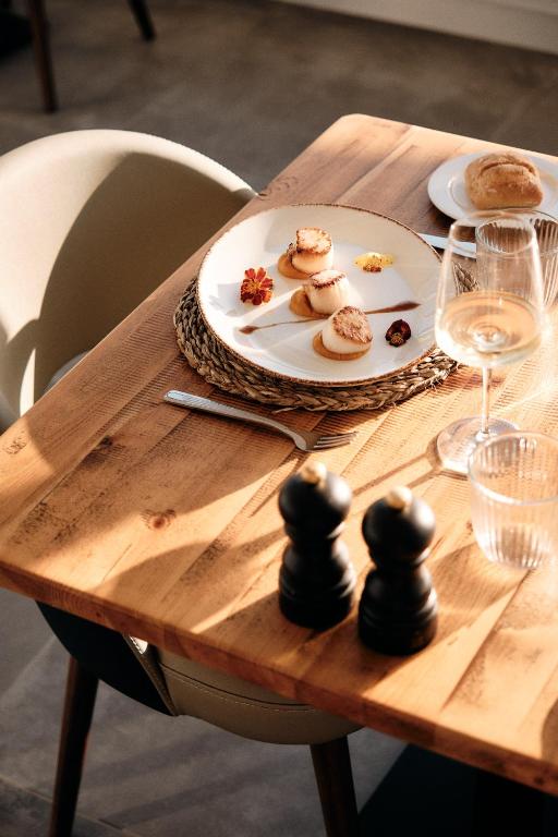 Eleganta galda klāšana ar gourmet ēdienu, vīna glāzi un melnajiem piparu traukiem. Ideāla atmosfēra svinībām vai romantiskai vakariņai.