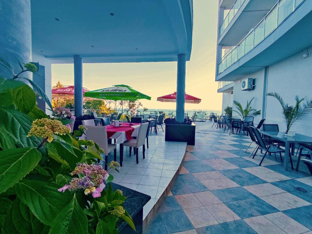 Terase ar skatu uz jūru, kurā ir galdi un krēsli, kā arī saulessargi. Apkārt ziedi un zaļumi, kas rada relaksējošu atmosfēru.