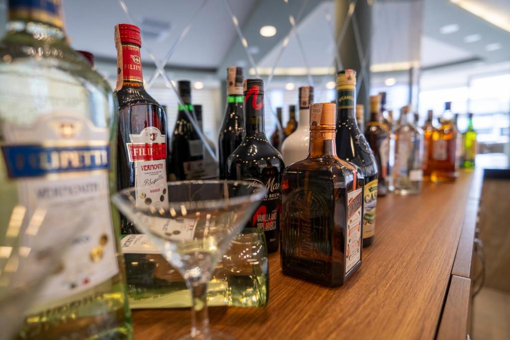 Alkohola dzērienu izvēle uz bāra letes, kurā redzami dažādi dzērieni un kokteiļu glāze.