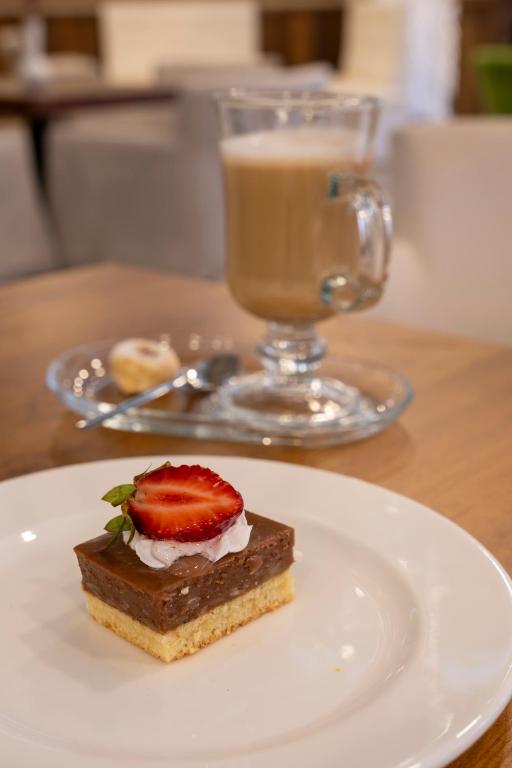 Šokolādes deserts ar zemenēm un putukrējumu, pasniegts kopā ar krēmīgu kafiju un sīkdatni.