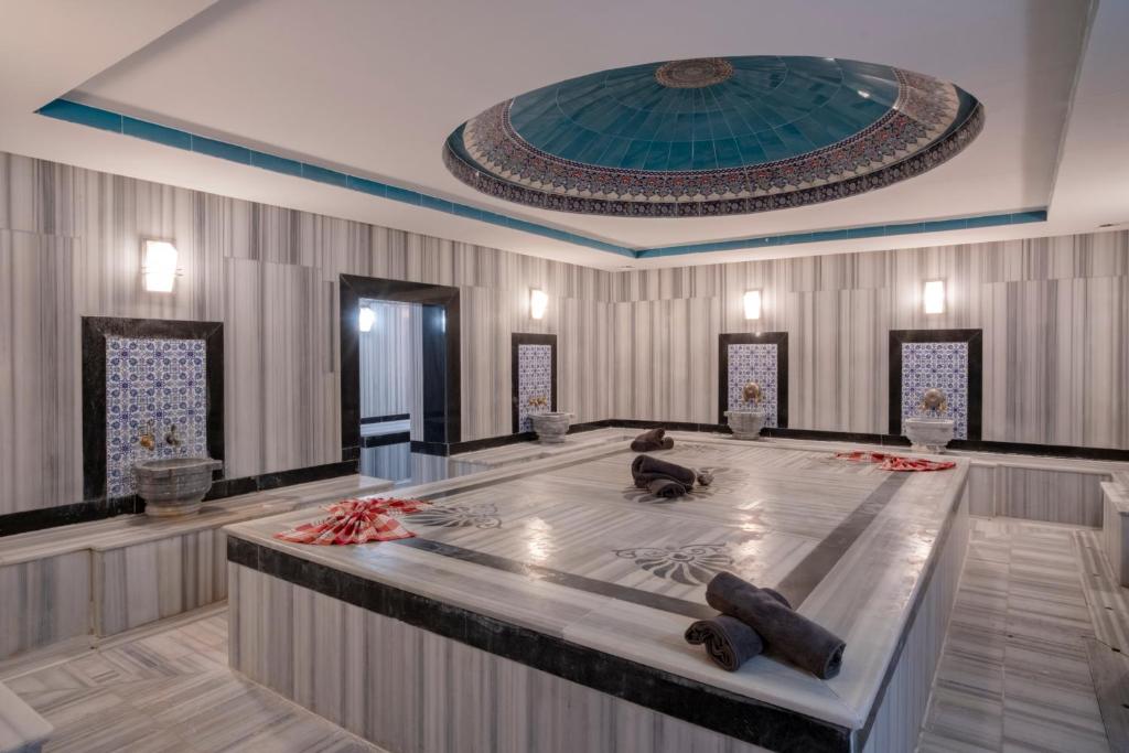 Elegants un moderns spa interjers ar marmora grīdu un dekoratīvām sienām. Telpas centrā atrodas liela masāžas zona ar dvieļiem un tradicionāliem elementiem.