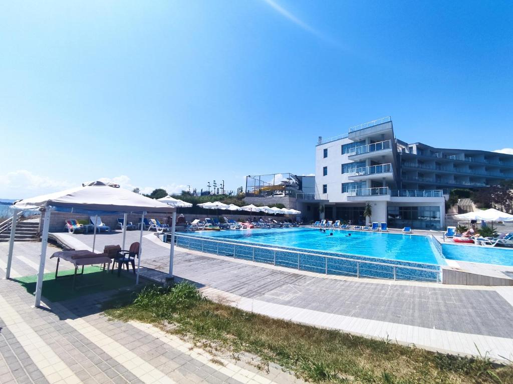 Baseins ar saulessargiem un viesnīcu fona, skaidra zila debesis. Ideāla vieta atpūtai un brīvā laika pavadīšanai.