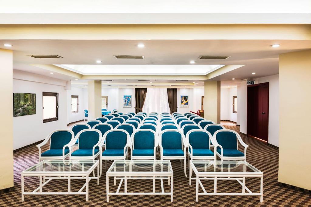 Konferenču telpa Asteria Collection Side ar zilo krēslu rindu un stikla galdiem.