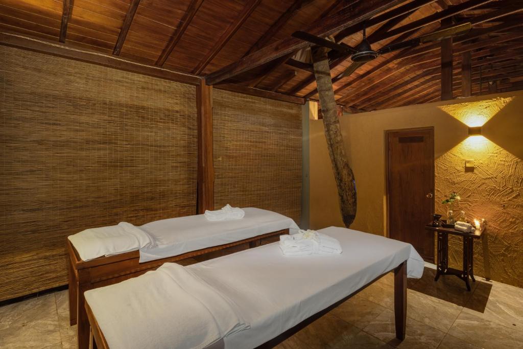Mierīga un relaksējoša spa telpa ar divām masāžas galdiem, koka griestiem un siltu apgaismojumu, kas rada patīkamu atmosfēru.