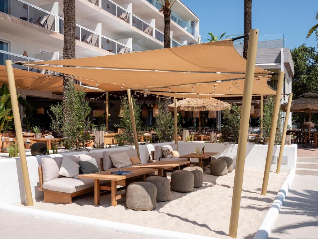 Pludmales kafijas galdiņš ar ērtām dīvāna vietām un saulessargiem, kas nodrošina relaksējošu atmosfēru. Apzaļumojums un moderna arhitektūra papildina šādu atpūtas vietu.