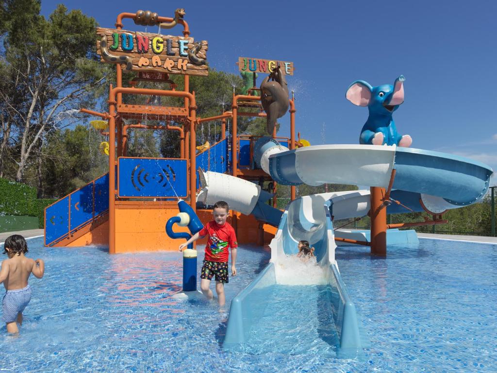 Ūdens atrakciju parks ar slidkalniņiem un jautriem bērniem, kas spēlējas ūdenī. Krāsainie dzīvnieku skulptūras piešķir jautrību un dinamiku videi.