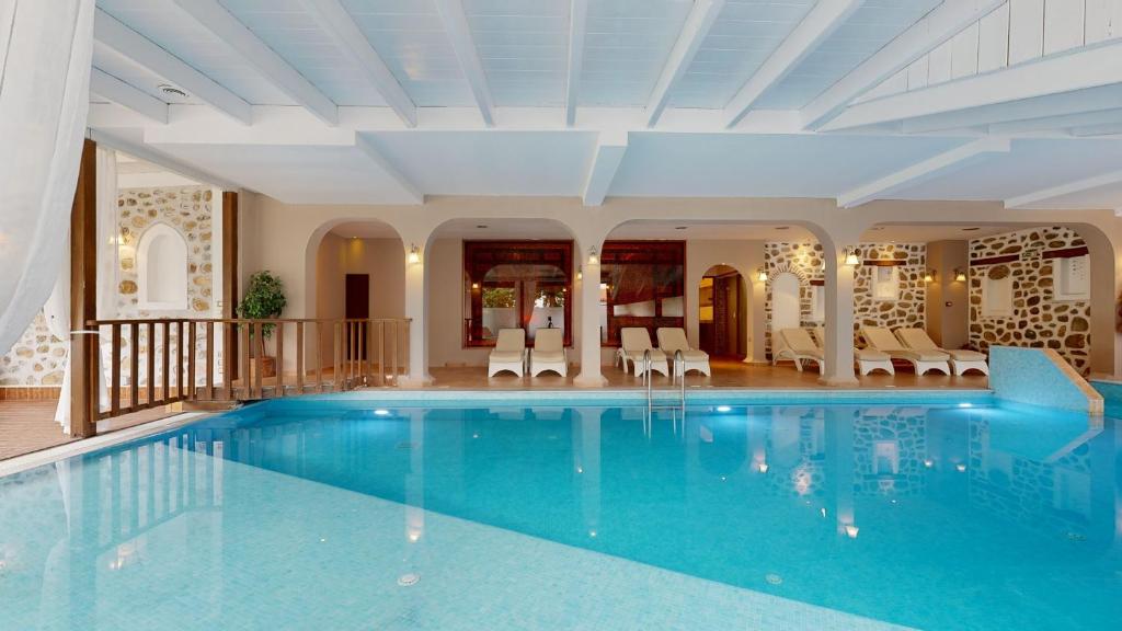 Mūsdienīgs iekštelpu baseins ar gaišām flīzēm un atpūtas zonu, kas veidota ar dabīgām akmens sienām un elegantām gultām. Ideāla vieta relaksācijai un atpūtai.