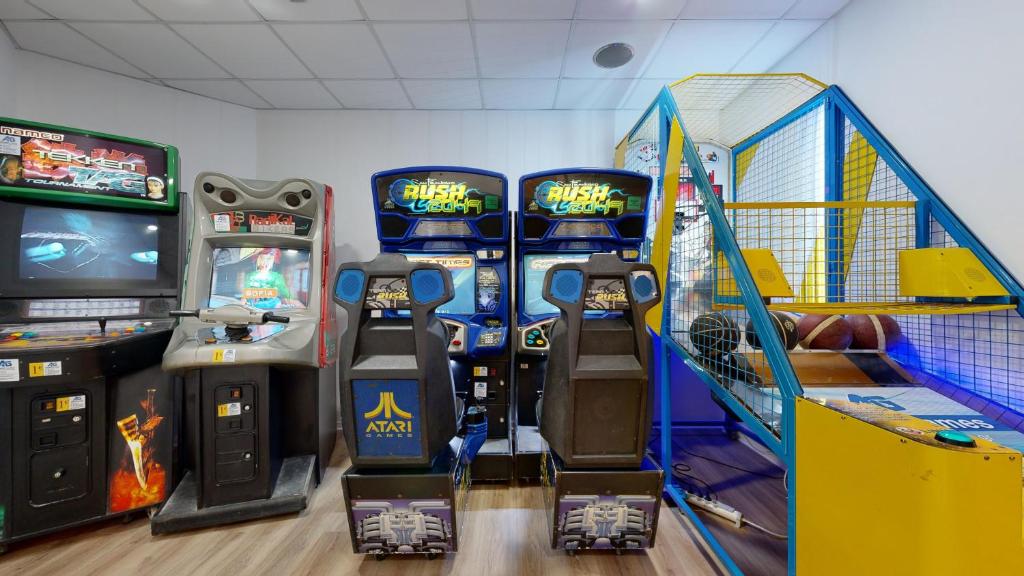 Arcade spēļu stūrītis ar klasiskajiem un mūsdienu spēļu automātiem, tostarp "Atari" un "Rush" spēlēm, kā arī sporta spēļu ierīci.
