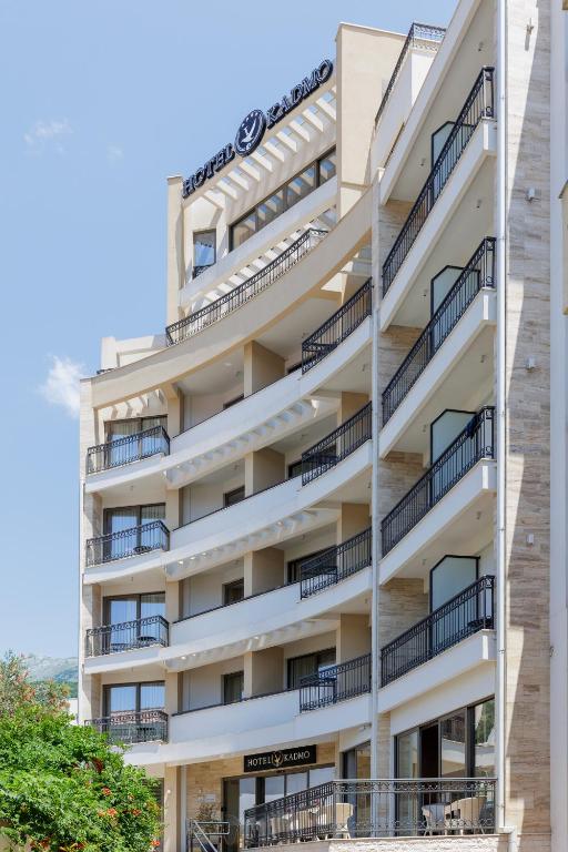 Moderns viesnīcas ēkas fasāde ar balkoniem un logiem, izceļot komfortu un dizainu, kas aicina viesus. Viesnīcas nosaukums redzams augšpusē.