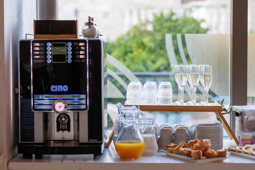 Kafijas automāts ar dzērieniem un elegantām glāzēm, kas novietotas uz galda, kopā ar brokastu uzkodām un dzērieniem.