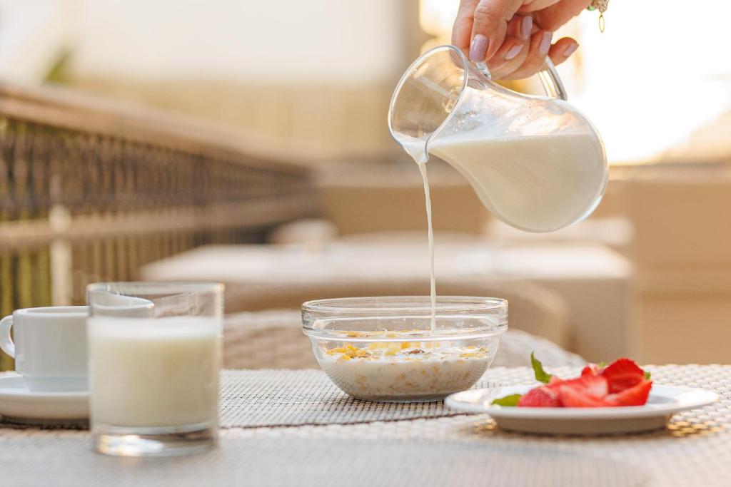 Svaigas brokastis ar pienu, kas tiek ielej traukā ar auzu pārslām, blakus ir kafija un zemenes.