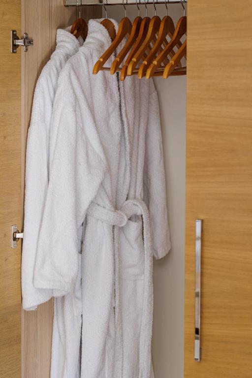 Balta peldmētelis, pakārts skapī uz koka pakaramā, veido mājīgu un relaksējošu atmosfēru. Skapis ar gludu virsmu un modernu rokturi papildina interjera dizainu.