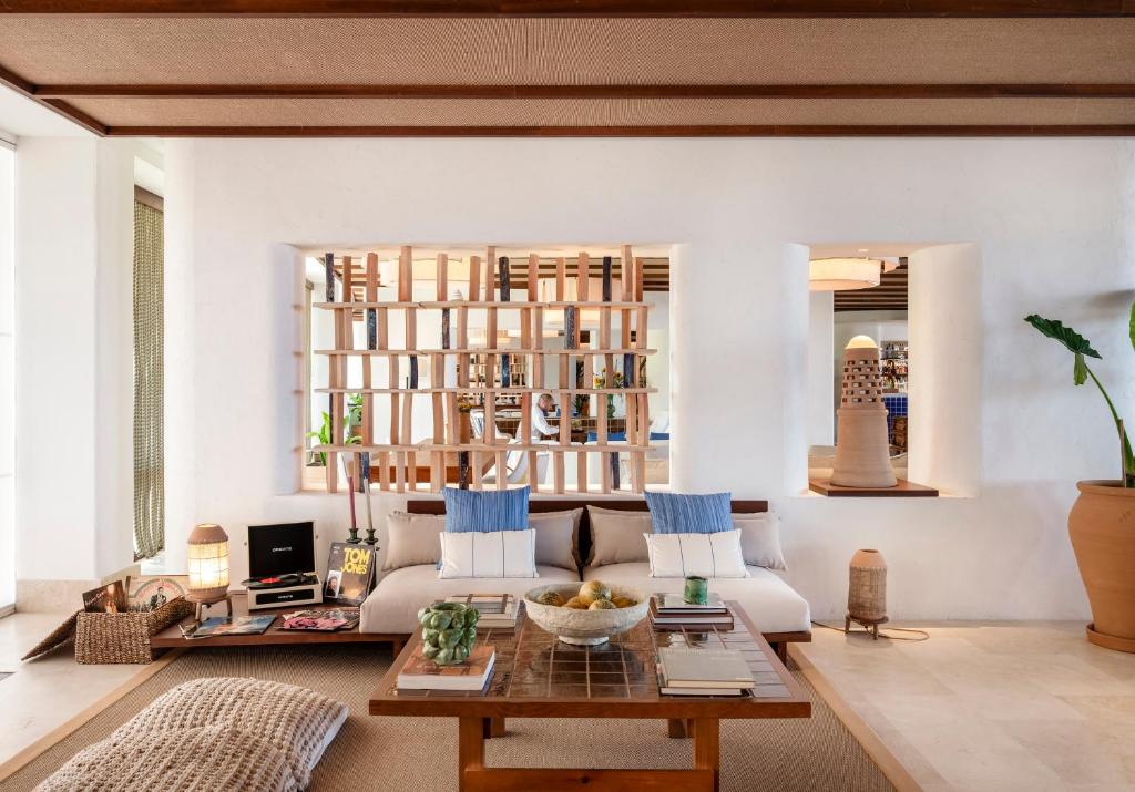 Mūsdienīga viesnīcas viesistaba ar skandināvu stila mēbelēm, koka detaļām un daudzveidīgiem dekoratīviem elementiem. Interjers izceļas ar gaišām krāsām un augu klātbūtni.