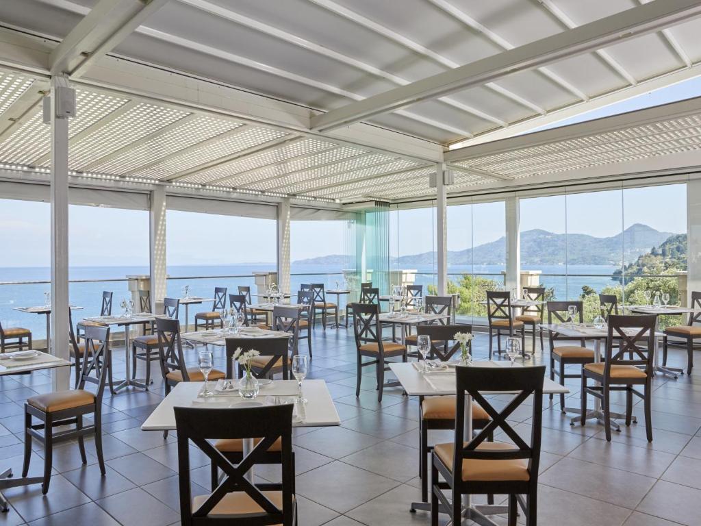 Moderns restorāns ar skatu uz jūru, gaišs interjers ar stikla sienām un elegantiem galdiem. Ideāla vieta relaksācijai un gastronomiskām baudām.