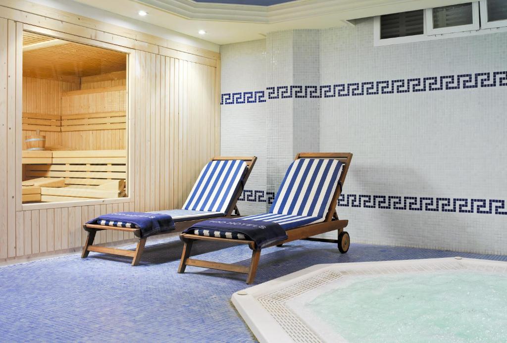 Spa telpa ar saunu un divām atpūtas krēslām, kas noklāti ar svītrainām dvieļiem. Grīda ir izklāta ar mozaīku, un stūrī atrodas burbuļvanna.