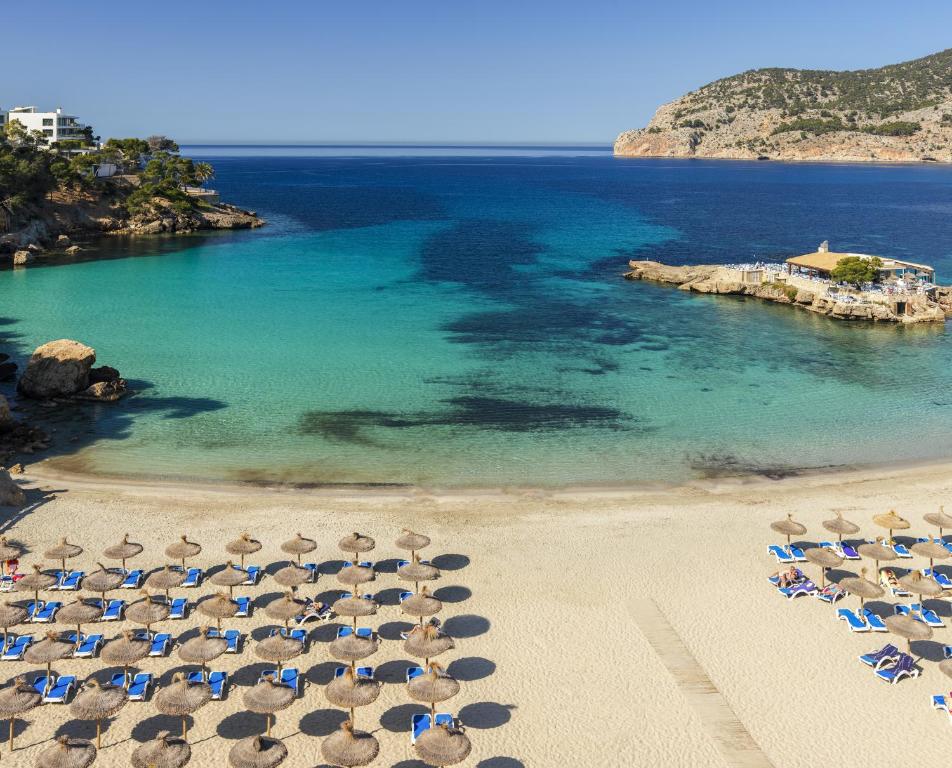 Skaista pludmale ar smiltīm un sauļošanās krēsliem, zilais ūdens un kalnu fons veido mierīgu atmosfēru. Ideāla vieta atpūtai un relaksācijai.