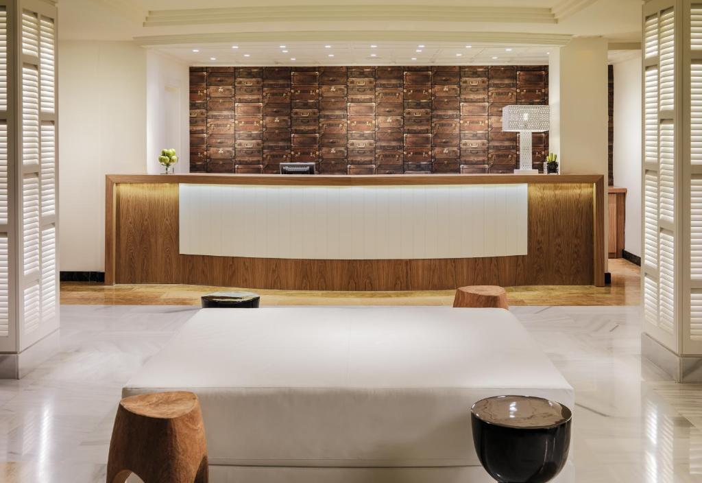 Mūsdienīgs viesnīcas reģistratūras interjers ar koka akcentiem un stilīgu apgaismojumu. Sienu fons rotāts ar vintage kastes, radot siltu un viesmīlīgu atmosfēru.