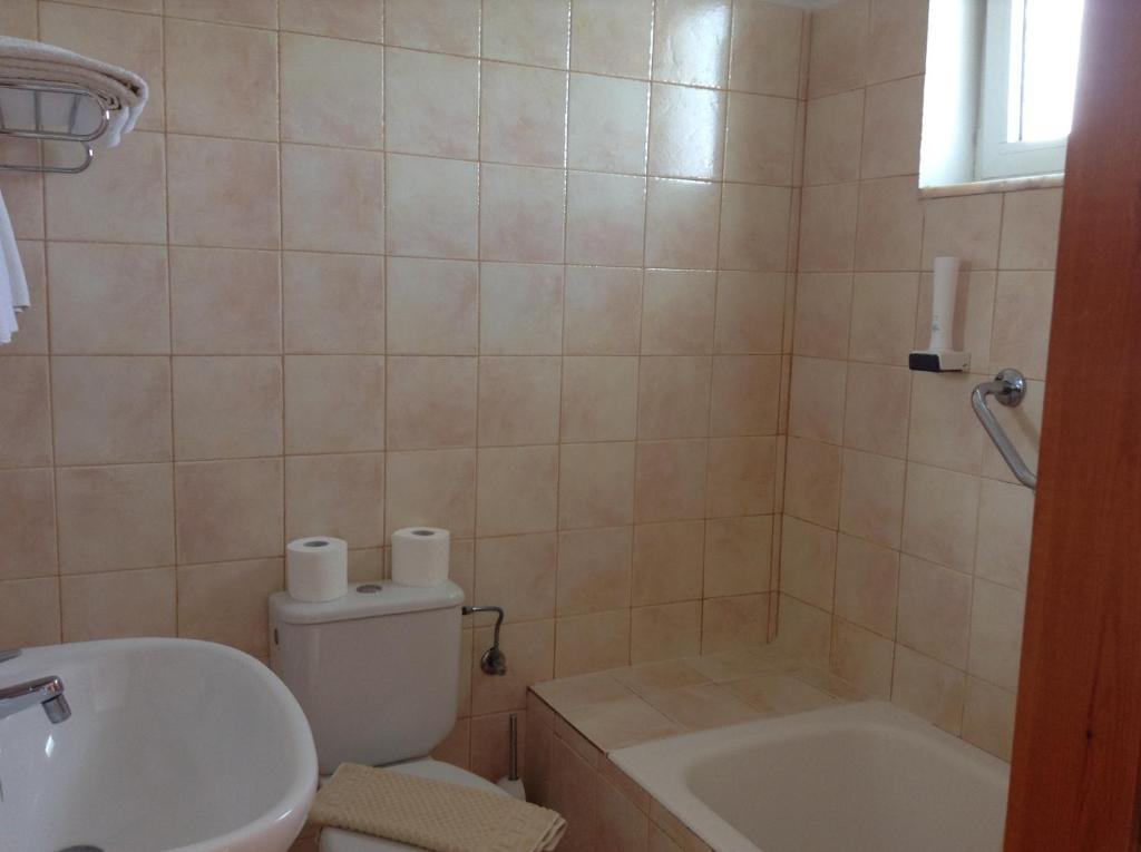 Vannas istaba ar flīzēm, tualetes podu un vannu, kas piedāvā pamata sanitāros apstākļus. Svaigi dvieļi un tualetes papīrs ir redzami.