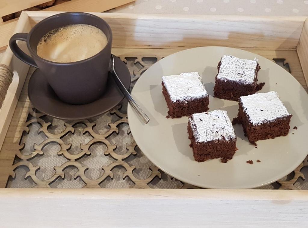 Svaigi cepti šokolādes kēksi ar pūdercukuru uz pelēka šķīvja blakus aromātiskai kafijai melnā krūzē.