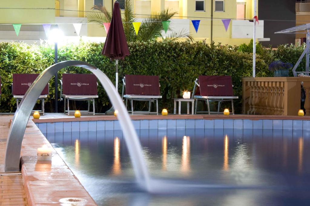 Nakts ainava pie baseina ar gaismas efektiem un sēdvietām, kas nodrošina relaksējošu atmosfēru. Sūknis rada ūdens plūsmu, kas piešķir dzīvīgumu šai viesnīcas teritorijai.