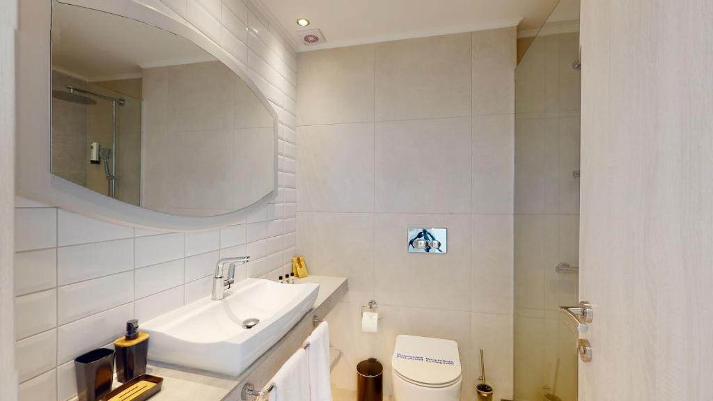 Mūsdienīgs viesnīcas vannas istabas interjers ar elegantu izskatu, ietverot modernu izlietni, lielu spoguli un dušas kabīni.