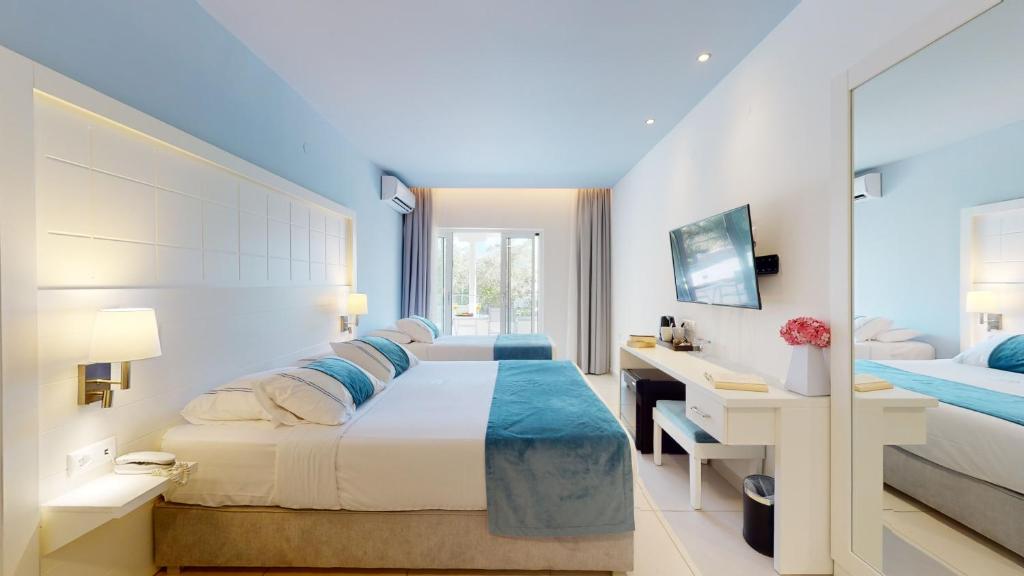 Mūsdienīga viesnīcas numura iekārtojums ar divām gultām, gaišām krāsām un skatu uz dārzu. Numurā ir televizors un rakstāmgalds, radot komfortablu un relaksējošu atmosfēru.