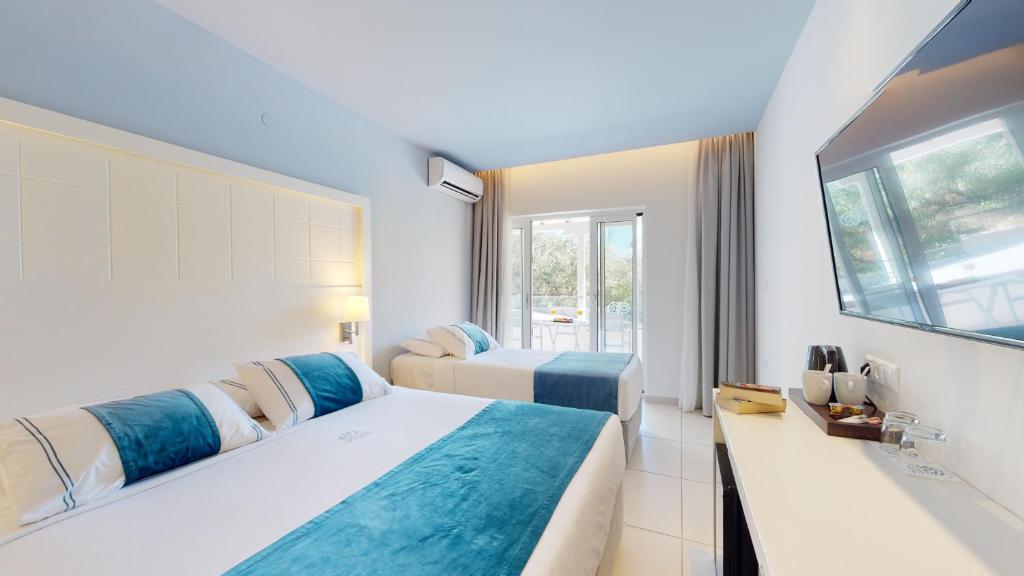 Mūsdienīga viesnīcas numura iekārtojums ar divām gultām, gaišām krāsām un moderno televizoru. Logi paver skatu uz ārpusi, radot patīkamu atmosfēru.