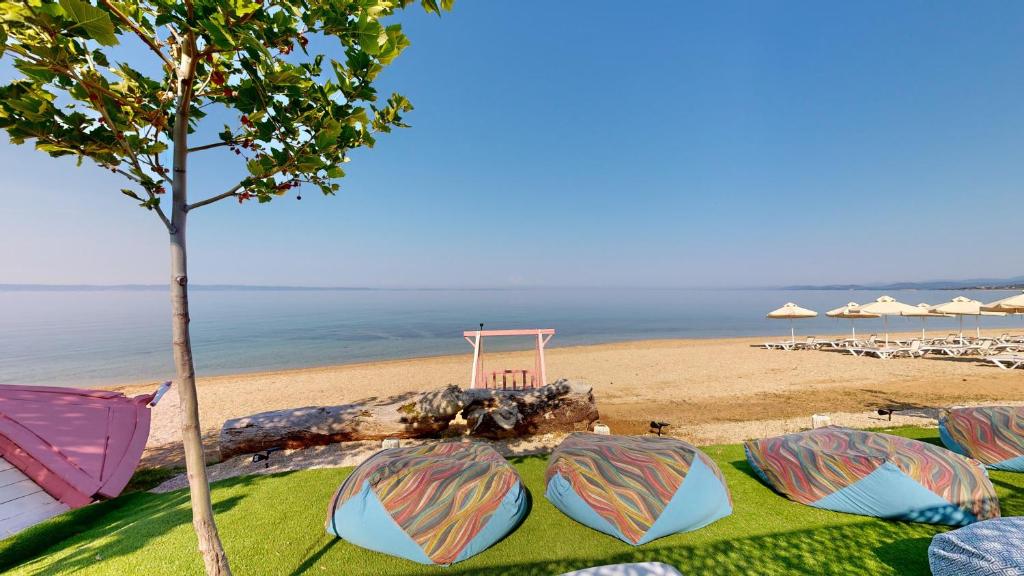 Pludmales ainava ar krāsainiem sēžamkrēsliem, koku un mierīgu jūru. Ideāla vieta relaksācijai un atpūtai.