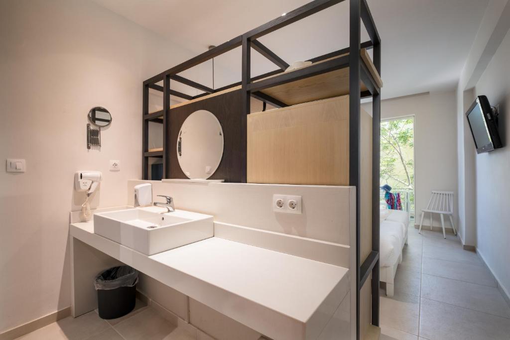 Mūsdienīgs vannas istabas interjers ar minimālistisku dizainu, kas ietver izsmalcinātu izlietni un spoguli, kā arī dabīgu apgaismojumu no loga.