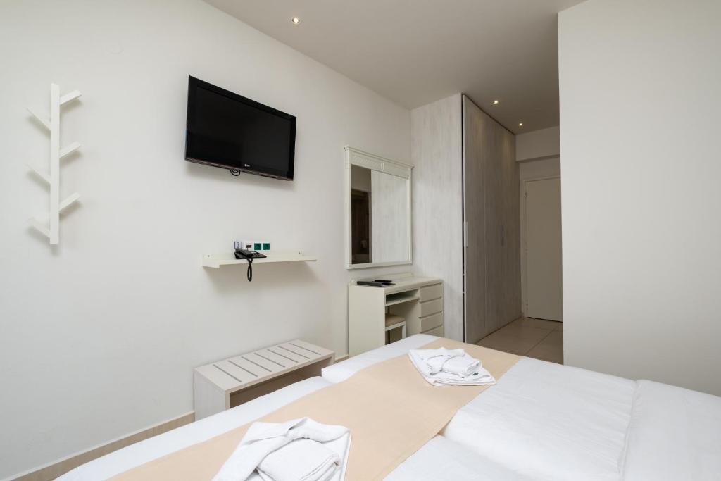 Mūsdienīga viesnīcas istaba ar televizoru, spoguļu un mēbeļu komplektu, kā arī gultu ar gultas veļu. Iekārtojums ir vienkāršs un gaišs.