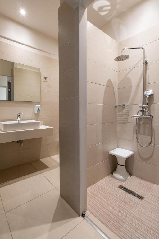 Moderns vannas istabas interjers ar dušu, izlietni un spoguli, kā arī minimālistisku dizainu un neitrālām krāsām.