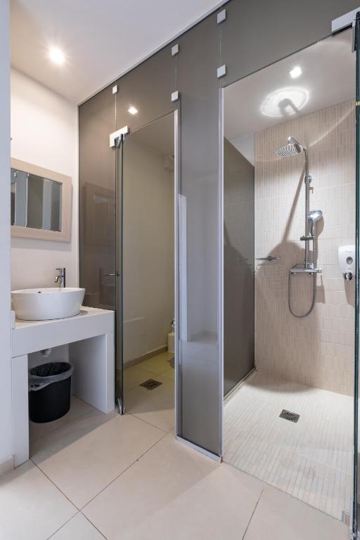 Mūsdienīga vannas istaba ar stikla dušas kabīni un elegantu izskatu, kurā redzams izlietnes komplekts un spogulis.