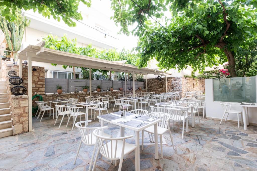 Ārtelpa restorānam ar baltām galdiem un krēsliem, ko ieskauj zaļumi un apstādījumi, piedāvā patīkamu atmosfēru ēšanai brīvā dabā. Gaisīga vide ar pārklājumiem un akmens sienām.