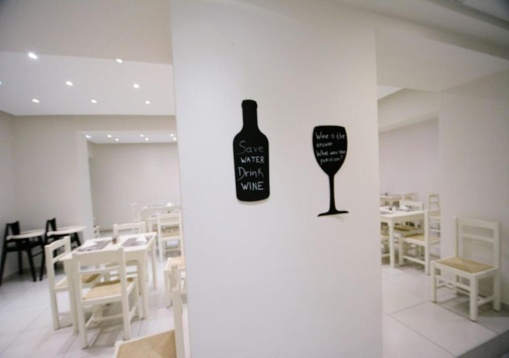 Sienas dekorācijas kafejnīcā ar tekstiem "Glabā ūdeni, dzer vīnu" un "Vīns ir atbilde, kāds bija jautājums?" uz gaišas sienas.