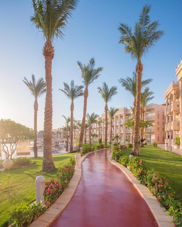 Pastaiga pa Albatros Palace Resort ar palmām un ziedošiem krūmiem.