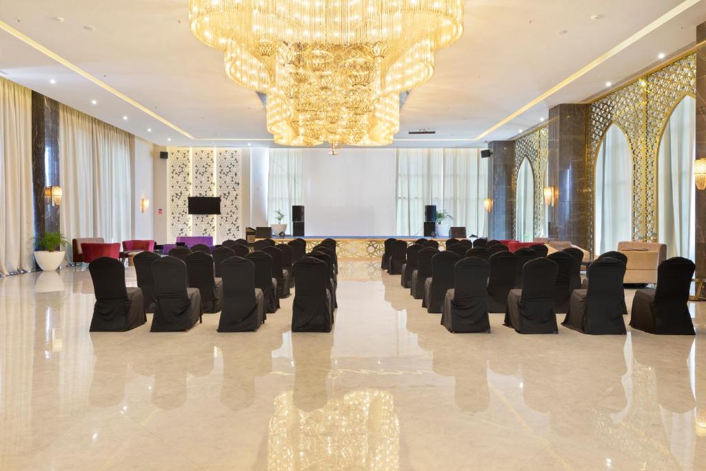 Moderns pasākumu zāle ar elegantiem melniem krēsliem, greznu lustru un mirdzošiem interjera elementiem. Ideāli piemērota konferencēm un svinībām.