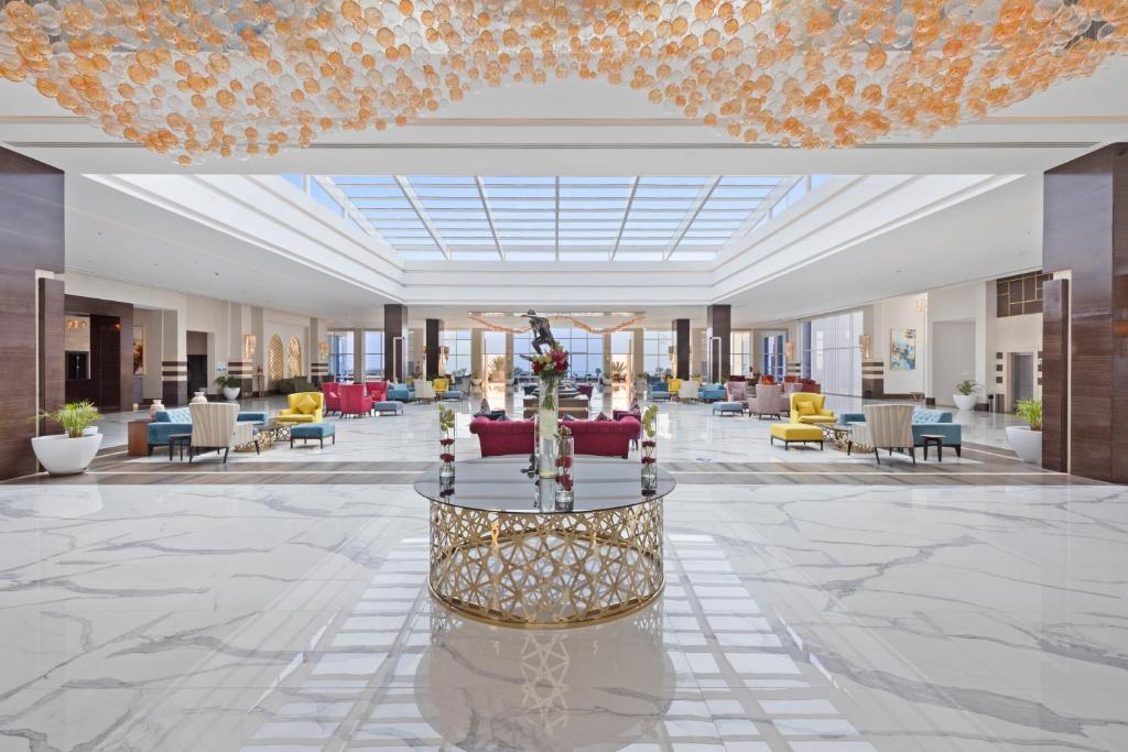 Moderns viesnīcas vestibils ar plašu atvērtu telpu, elegantu mēbeļu izkārtojumu un izsmalcinātu gaismas ķermeni. Gaiši toņi un mūsdienīga arhitektūra rada viesmīlīgu atmosfēru.