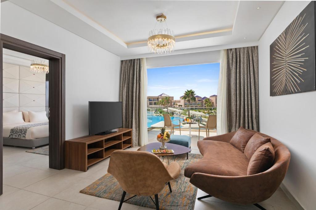 Mūsdienīgs viesnīcas numurs ar elegantām mēbelēm, televizoru un skatu uz baseinu un dārzu. Logā ieplūst dabiska gaisma, radot patīkamu atmosfēru.