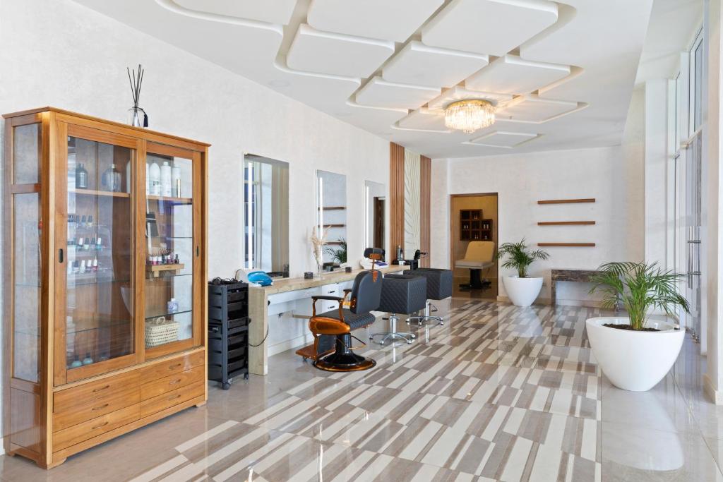 Moderns frizētavas interjers ar elegantu dizainu, kurā redzami frizieru krēsli, spoguļi un stila elementi. Gaismas un augi piešķir telpai dzīvīgumu.