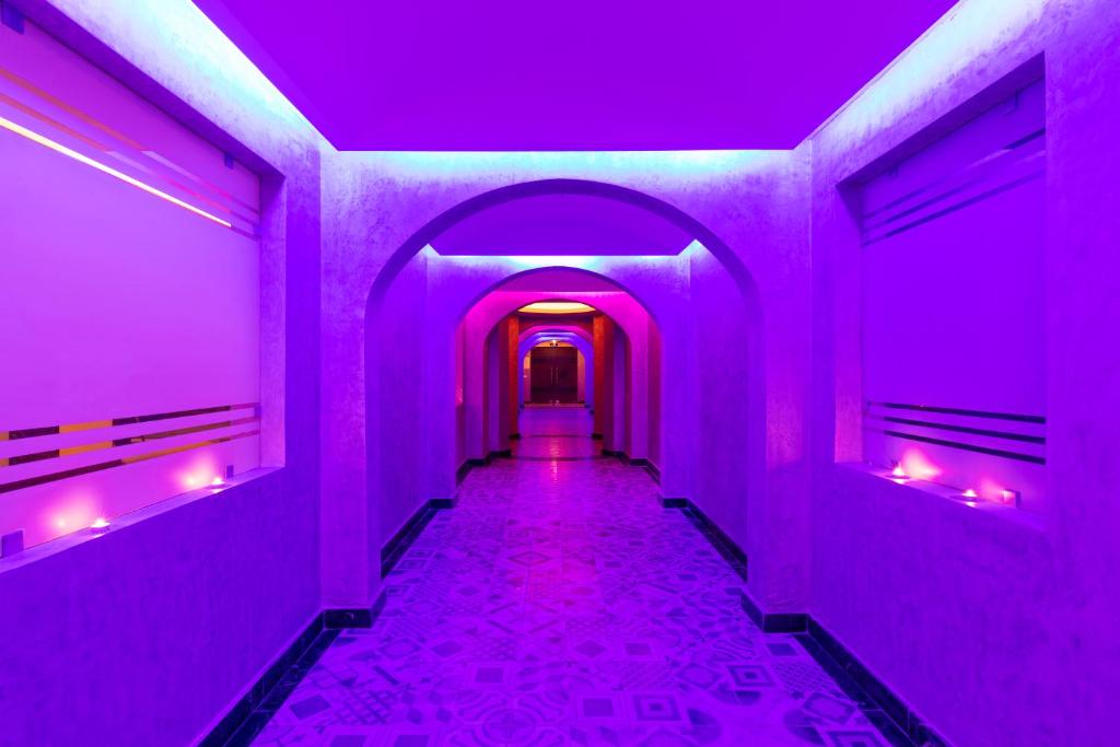 Mūsdienīgs koridors ar purpura apgaismojumu, kas rada noslēpumainu atmosfēru. Šī arhitektūra apvieno eleganci un modernitāti.