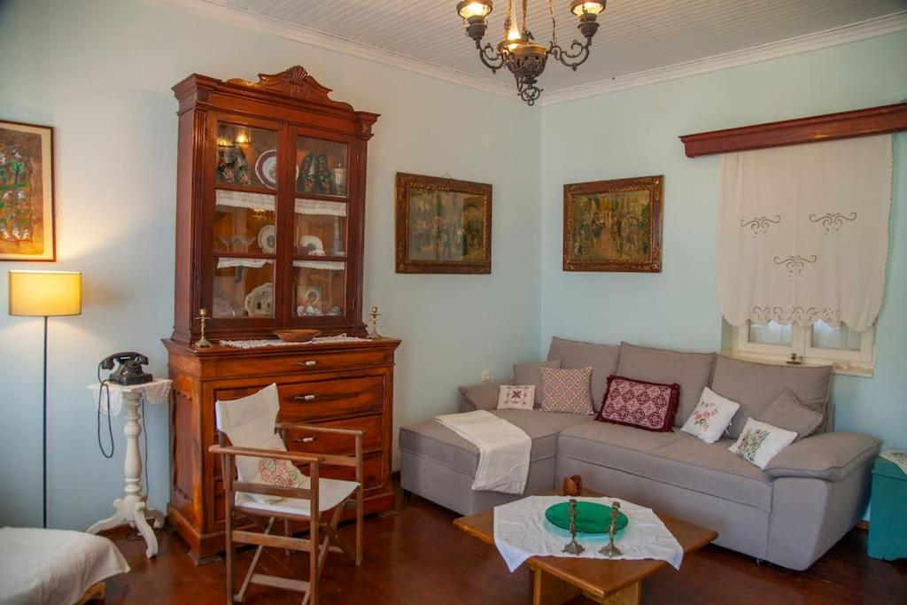 Skaista un mājīga viesistaba ar vintage mēbelēm, tostarp koka vitrīnu un ērtu pelēku dīvānu. Interjeru papildina mākslas darbi un silta apgaismojuma elementi.