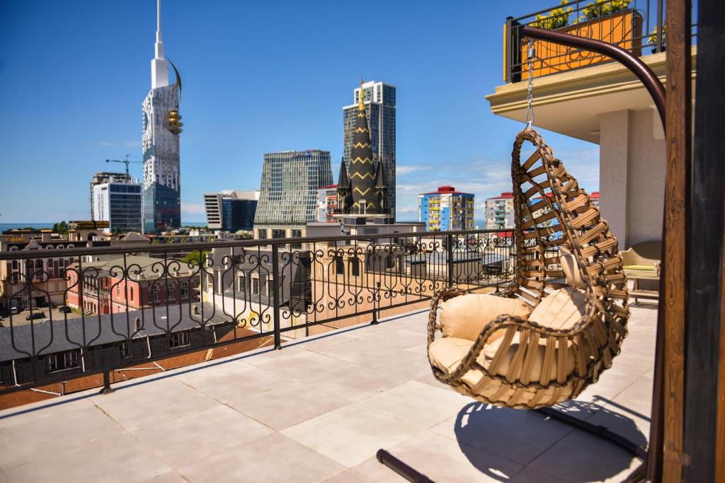 Terases skats ar šūpojošu krēslu un modernām pilsētas ēkām. Ideāla vieta relaksācijai un izbaudīšanai.